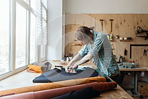Craftsman drawing scheme lining for bag on tissue creating leatherwork at studio leather workshop photo