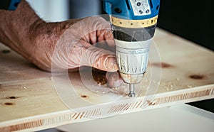 Craftsman is drilling in wood with drilling machine