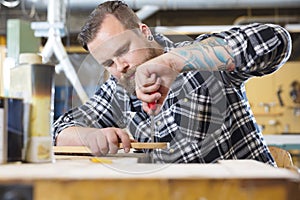 Craftsman files wooden guitar neck in workshop