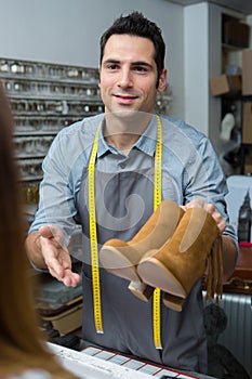 Craftsman giving boots to female customer