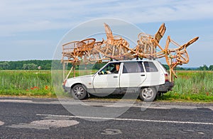 Craftsman having a short break while transport wicker-work on a roof of a small car