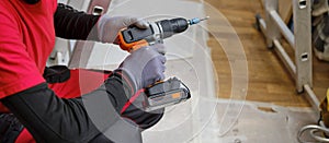 Craftsman holding a screwdriver drill ready to perform home renovation. Worker in work clothes on a construction site on an