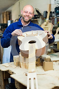 Craftsman holding unfinished guitar