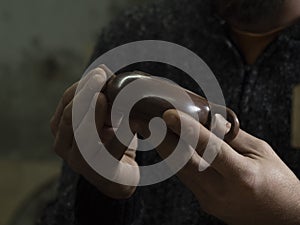 A craftsman holds a traditional Chinese teapot made of Yixing clay. Handmade clay teapot for Chinese tea ceremony. brown pottery