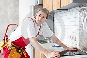 craftsman installs hob in kitchen. Household Appliance Installation Services Concept.