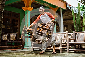 a craftsman lifts a shiny polished bamboo chair