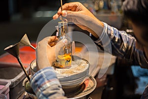 Craftsman makes souvenirs in a bottle using colored sand