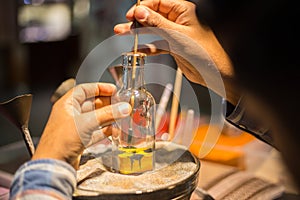 Craftsman makes souvenirs in a bottle using colored sand