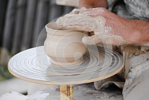 Craftsman making vase from fresh wet clay on pottery wheel