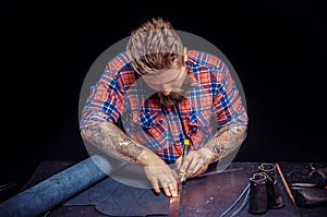 Craftsman performing leatherwork on a new product piece in the workplace