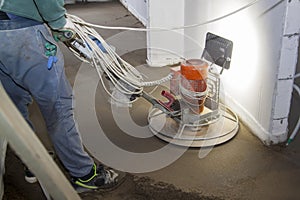 craftsman performing and polishing sand and cement screed floor on construction site of new apartment. Sand and cement floor