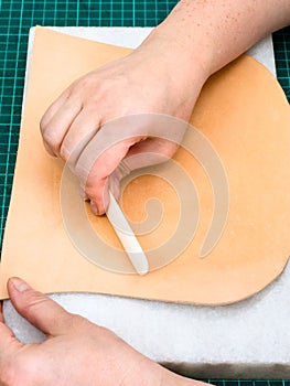 Craftsman polishes leather using flat slicker photo