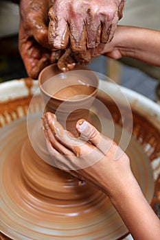 Craftsman potter hands of teacher and pupil