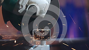 Craftsman in protective gloves working with grinder at industrial plant, man grinding iron detail, sparks flying around