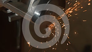 Craftsman in protective gloves working with grinder at industrial plant, man grinding iron detail, sparks flying around