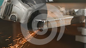 Craftsman in protective gloves working with grinder at industrial plant, man grinding iron detail, sparks flying around