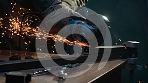 Craftsman in protective gloves working with grinder at industrial plant, man grinding iron detail, sparks flying around.