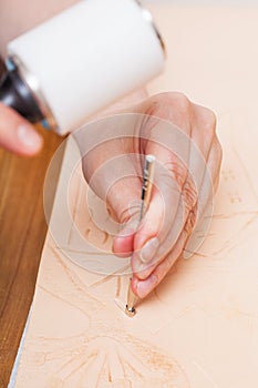 Craftsman puts pattern on leather by stamping tool