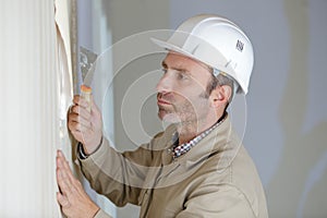 Craftsman removes wallpaper with spatula