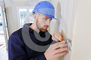Craftsman removes wallpaper with spatula
