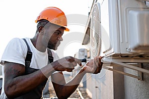 Craftsman repairing air conditioner with screwdriver on roof