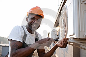 Craftsman repairing air conditioner with screwdriver on roof