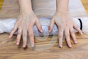 Craftsman rolls a mat with gloves for fulling