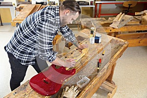 Craftsman sanding a guitar neck in wood at workshop