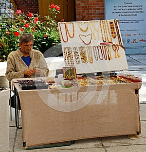 Craftsman sells jewelry made of amber near Museum of Amber in Kaliningrad