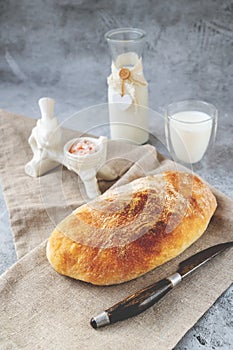 Craftsman sliced toast bread with butter on a wooden cutting board and milk. Simple breakfast on a gray concrete background. Close