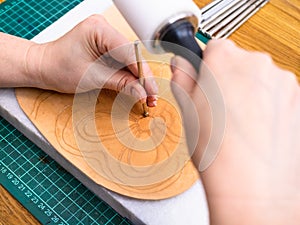 Craftsman stamps the floral ornament on leather