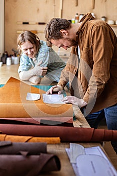 Craftsman unwrapping bundle of stuff natural material working at leather workshop. Leatherwork photo