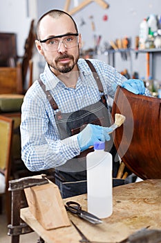 Craftsman using brush for lacquering armchair