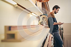 Craftsman using cell phone in his workshop