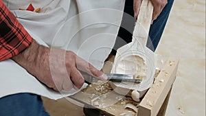 A craftsman woodcarver creates a spoon. Close-up of male hands with a woodworking tool. The man at work. Use a sharp