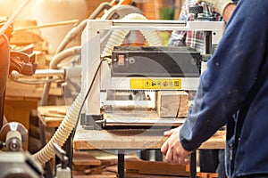 Craftsman woodworking at carpentry with lots of modern professional power tools. Man using thicknessing machine and circular saw