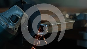 Craftsman working with grinder at industrial plant, man grinding edge of iron detail, sparks flying around and falling