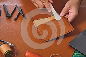 Craftsman working leather in his workshop creating a wallet
