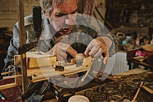 Craftsman in workshop making wooden toy, a wooden model of sailboat. Carpenter sticks a wooden part on a wooden ship