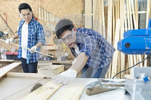 Craftsmans working together at carpentry shop. Carpenter working with circular saw at carpentry workshop