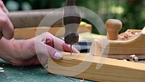 CraftsmCarpenter woman using a hammer to hitting a nail into wooden plank.an4