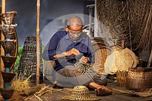 Craftsmen of Thai. An old man who is the craftsmanship in Buriram Province Weaving a basket of bamboo. Craftsmanship that has been
