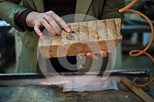 A craftsperson examines a uniquely textured piece of burl wood, appreciating its complex patterns and potential for a