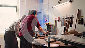 Craftsperson uses angle grinder on wood after checking schematics