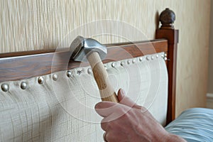 craftsperson using a hammer to secure tacks on a headboard