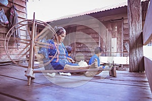 Craftsperson working. Old woman process homespun cotton cloth weaving in the community. Senior women spinning natural cotton
