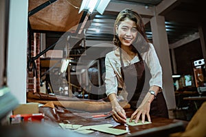 Craftswoman in apron working with leather belt manufacturing process