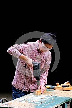 Craftswoman drilling a hole with an electric drill machine in wooden plank. Woodwork, DIY, gender equality concept