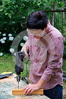 Craftswoman drilling wooden plank to make a hole. Gender equality, DIY, woodwork concept