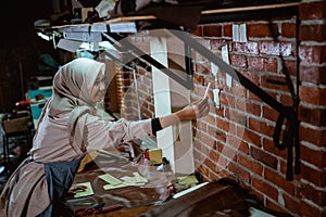 Craftswoman in veil makes sticky notes on wall while working